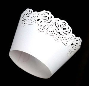 Macro shot of white laser-cut cupcake wrapper with elegant rose flower pattern detail