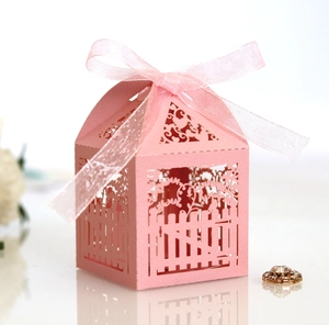 Detail of pink laser-cut wedding favor box with fence pattern and chiffon ribbon