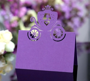 Detail of laser-cut purple princess seat card featuring a pumpkin carriage and heart design