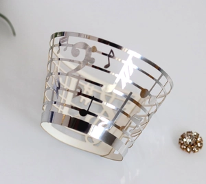 Macro shot of silver mirror laser-cut cupcake wrapper with musical notes and staff lines