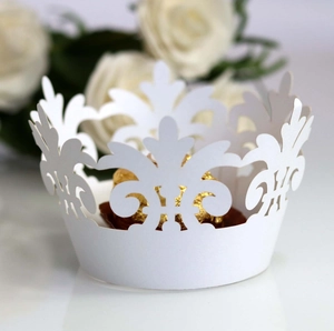 Macro view of white laser-cut crown lace cupcake wrapper with decorative gold chocolates