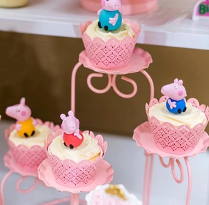 Pink laser cut hollow cupcake wrappers with cute pig party toppers on a tiered metal stand