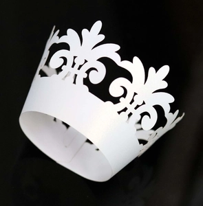 Macro detail of laser-cut white pearlescent paper cupcake liner with vine patterns