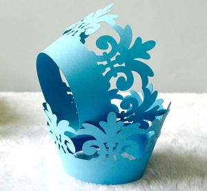 Close-up of laser-cut light blue cupcake wrappers with elegant filigree pattern detail