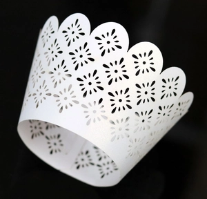 Macro view of white laser-cut cupcake liners with intricate floral lace and wave patterns