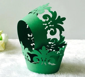 Macro shot of green laser-cut cupcake wrappers with elegant hollowed-out floral patterns
