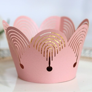 Pink laser-cut cupcake wrapper with hollow crown lace design and a chocolate center