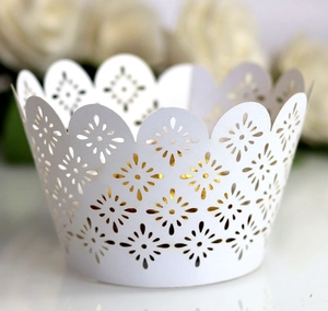 Macro view of white laser cut cupcake wrappers with star floral patterns and wavy edges