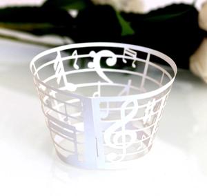 Macro detail of laser-cut musical notes and staff pattern on white cupcake wrappers