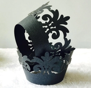 Macro detail of laser-cut black lace cupcake wrappers with elegant vine patterns