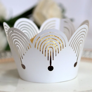 Elegant white laser-cut cupcake wrappers with intricate hollow arches and crown edges