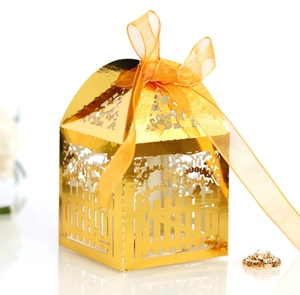 Macro detail of laser-cut gold gift box with floral fence pattern and orange ribbon bow