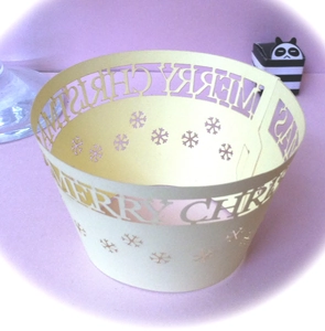 Macro shot of laser-cut Merry Christmas cupcake wrappers with elegant snowflake patterns