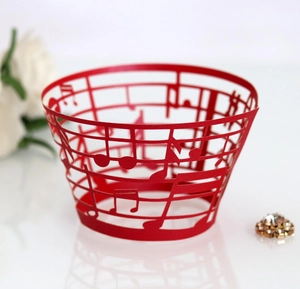 Laser-cut red cupcake wrapper featuring intricate musical notes and staff line patterns