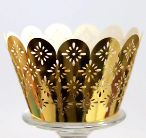 Elegant gold laser-cut cupcake wrappers with floral patterns for festive dessert displays