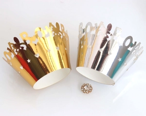Gold and silver laser-cut cupcake wrappers with royal lettering and star patterns