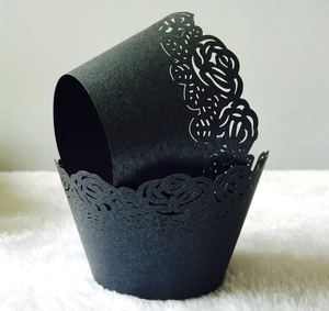 Close-up of matte black laser-cut cupcake wrappers with elegant rose lace patterns