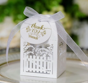 Detail of white laser-cut candy box with elegant floral pattern and thank you tag