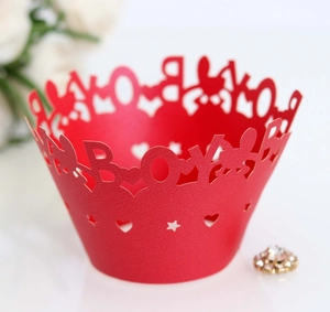 Detail of red laser-cut cupcake wrapper featuring BOY lettering and heart patterns