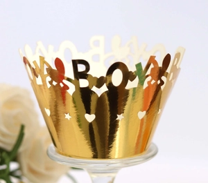Detail view of golden hollow-out cupcake wrapper with BOY letters for baby shower party