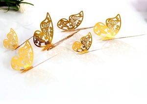 Macro shot of 3D gold hollow butterfly wall stickers with intricate laser-cut wing patterns