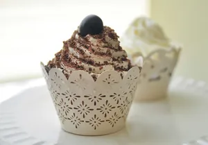 Hollow lace cupcake wrappers in cream white paper with delicate floral cutouts