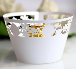 Detail view of laser-cut paper cupcake wrappers with teapot and floral lace patterns