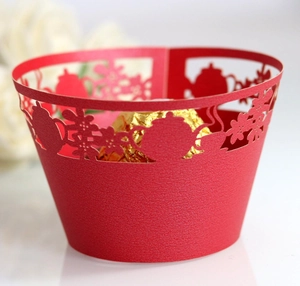 Detail of red laser-cut cupcake wrapper with hollow teapot and flower patterns