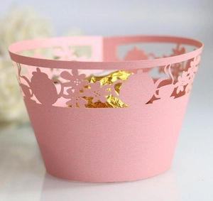 Detail of pink laser-cut cupcake wrapper with teapot and floral patterns for events