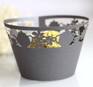 Detail of laser-cut tea party cupcake wrappers in dark grey with teapot and floral patterns