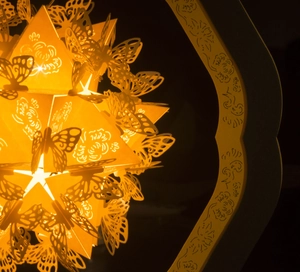 Detail of warm glow LED star lamp featuring laser-cut butterfly patterns and a carved base