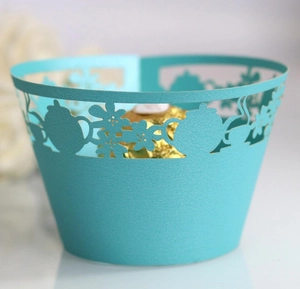 Close-up of laser-cut cupcake wrapper with pearlized finish and teapot floral patterns
