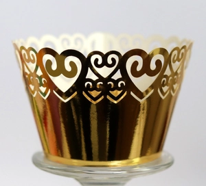 Detailed macro of golden laser-cut cupcake wrapper with heart pattern on glass stand