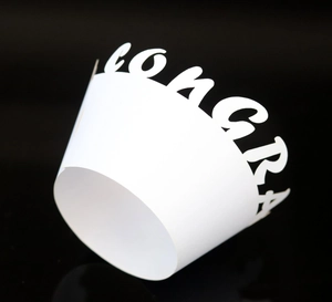 White laser-cut paper cupcake wrapper featuring CONGRATS lettering for celebrations