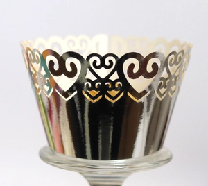 Macro detail of laser-cut heart pattern on silver metallic cupcake wrappers for weddings