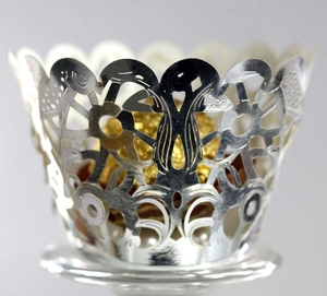 Macro shot of laser-cut silver hollow cupcake wrapper with intricate floral patterns