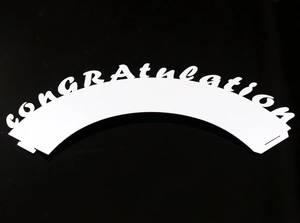Laser-cut white cupcake wrapper featuring a hollowed-out congratulation text design