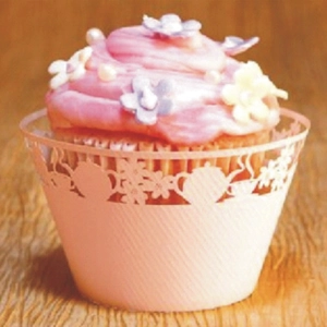 Pink cupcake wrapper with hollow teapot lace pattern on rustic wooden background