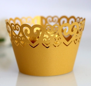 Macro detail of laser-cut heart pattern on golden pearlescent cupcake wrappers
