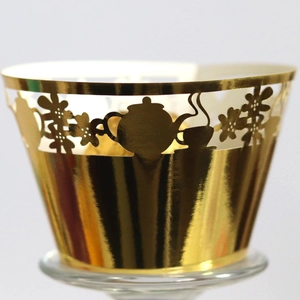 Golden laser-cut cupcake wrappers featuring teapot and floral designs for baking decor