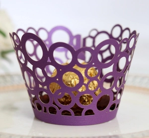 Detail of laser-cut dark purple cupcake wrapper with circle pattern on a ceramic plate