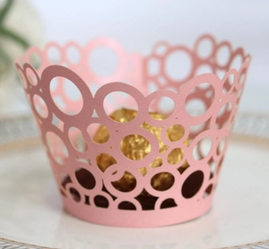 Detail of pink laser-cut cupcake wrapper with hollow circle patterns and pearl finish
