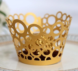 Detailed laser-cut gold cupcake wrapper featuring a circular hollow pattern on a plate