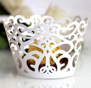 Detail of white laser-cut cupcake wrapper with elegant floral lace pattern for weddings