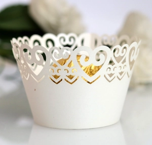 Detailed laser-cut white cupcake wrapper with heart patterns for wedding party decor