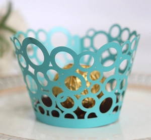 Detail of laser-cut light blue cupcake wrapper with decorative round hole patterns