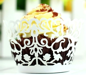 Macro shot of laser-cut white cupcake wrapper with elegant floral vine hollow patterns