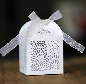 Macro shot of laser-cut hollow pattern and white ribbon bow on elegant wedding candy box