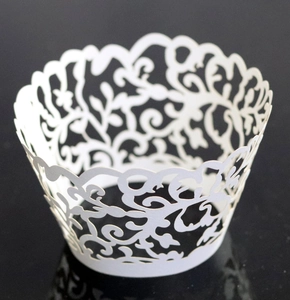 Macro detail of white laser-cut cupcake wrappers with elegant floral vine patterns