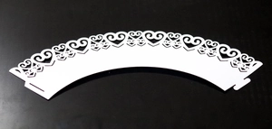 Detail showing white heart-shaped laser-cut cupcake wrappers with lace hollow design